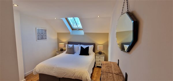 king size en-suite bedroom, skylight over the bed, 2 bedside tables with lamps, a mirror on the right hand wall