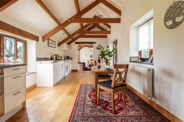 Interior of Linhay with vaulted ceiling and beams, kitchen and lounge beyond