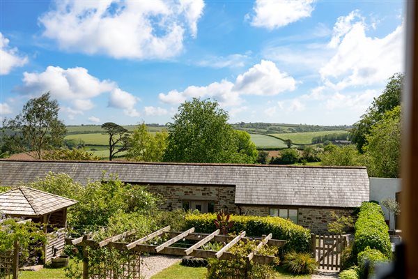 View of Linhay with courtyard garden in front and farm fields beyond.