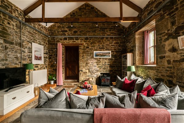 Living room with TV and woodburner in a luxury farm holiday cottage