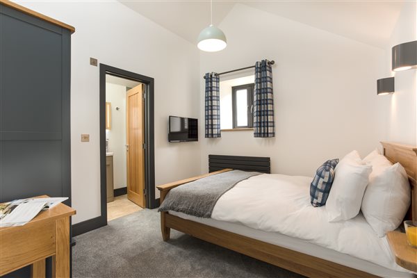 Double en-suite bedroom with oak framed bed and blue wardrobe and console table