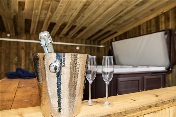 Champagne flutes with wine bucket in foreground and open hot tub