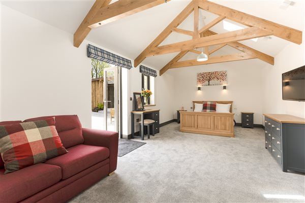 King en-suite bedroom, with red sofa, blue and oak topped 6 drawer unit and dressing table & stool