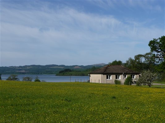 self-catering cottage by a field and looking onto a loch in argyll