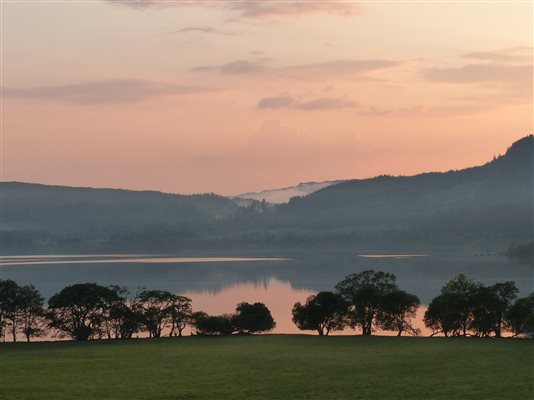 subtle, peachy sunset reflecting on a loch in Scotland