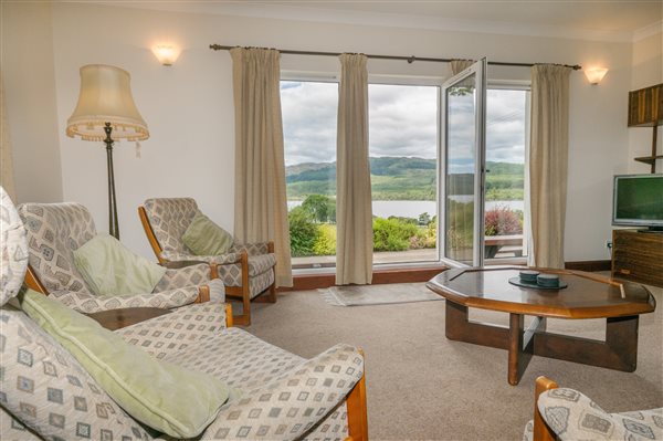 large sitting room with view to a loch through 3 long windows