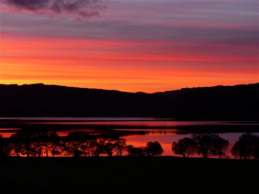 a red sunset reflecting on a loch in Scotland