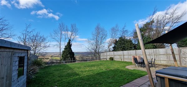 garden with hot tub to the right and views out over the moss valley in the distance