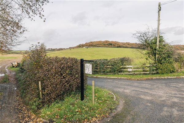 Entrance to private drive from main road, farm sign, fields