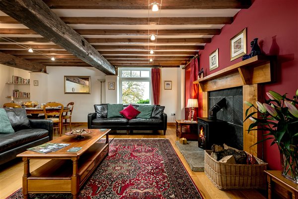 Spacious living room with leather sofas and wood burning stove