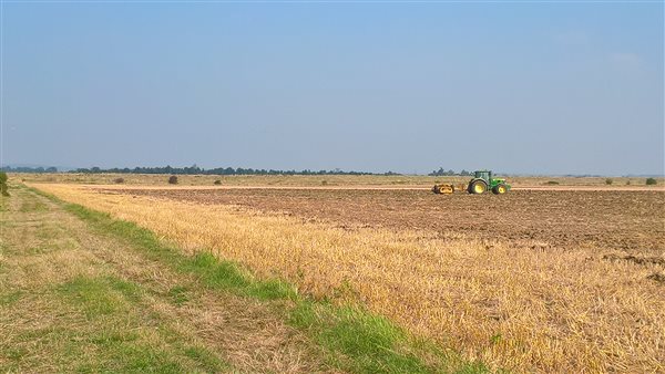 Tractor on the field. View towards sea wall Tractor on the field. View towards sea wall
