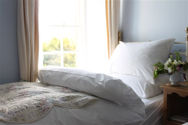 A single bed with beautiful organic bed linen and feather duvet