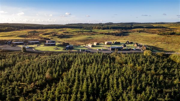 Aerial view of luxury countryside glamping accommodation surrounded by lush green woodland, rolling hills and peaceful rural scenery. Aerial view of luxury countryside glamping accommodation surrounded by lush green woodland, rolling hills and peaceful rural scenery.
