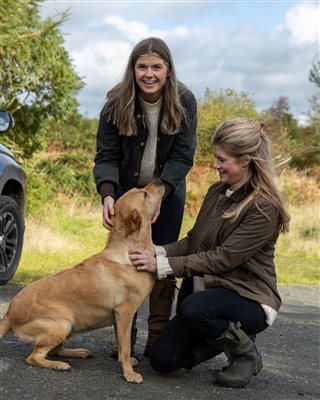 Two women petting a friendly golden dog outdoors, highlighting the welcoming, dog-friendly atmosphere of a countryside glamping getaway. Two women petting a friendly golden dog outdoors, highlighting the welcoming, dog-friendly atmosphere of a countryside glamping getaway.