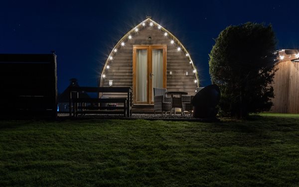 Luxury glamping pod illuminated by fairy lights at night, featuring a private outdoor seating area and peaceful countryside surroundings. Luxury glamping pod illuminated by fairy lights at night, featuring a private outdoor seating area and peaceful countryside surroundings.