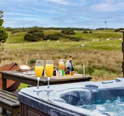 Private bubbling hot tub at a luxury countryside glamping pod, with drinks ready to enjoy and beautiful panoramic views across peaceful green fields. Private bubbling hot tub at a luxury countryside glamping pod, with drinks ready to enjoy and beautiful panoramic views across peaceful green fields.