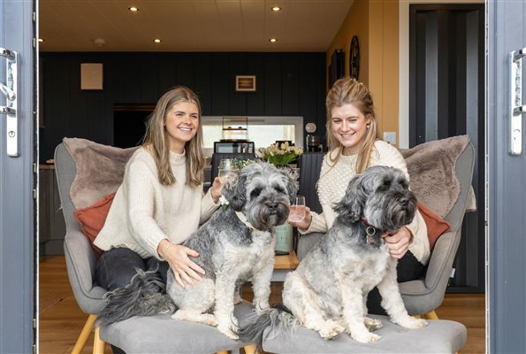 Two guests relaxing with their dogs in the comfortable living area of a luxury cabin at Galloway Retreats, Dumfries and Galloway Two guests relaxing with their dogs in the comfortable living area of a luxury cabin at Galloway Retreats, Dumfries and Galloway