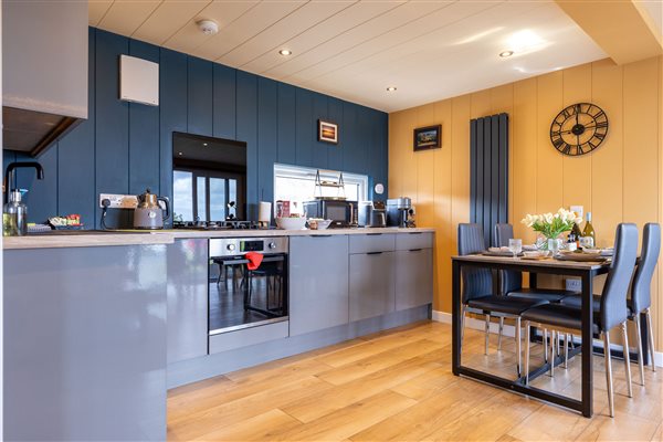 Modern fully equipped kitchen and dining area at Galloway Retreats luxury cabins, featuring contemporary grey cabinets, built-in oven and stylish dining table. Modern fully equipped kitchen and dining area at Galloway Retreats luxury cabins, featuring contemporary grey cabinets, built-in oven and stylish dining table.