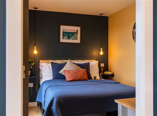 Luxury cabin bedroom at Galloway Retreats featuring a comfortable double bed, blue bedding, soft bedside lighting and stylish contemporary decor. Luxury cabin bedroom at Galloway Retreats featuring a comfortable double bed, blue bedding, soft bedside lighting and stylish contemporary decor.