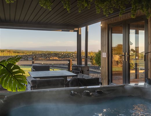 Private outdoor hot tub overlooking the covered terrace and glass doors of a luxury cabin at Galloway Retreats, Dumfries and Galloway. Private outdoor hot tub overlooking the covered terrace and glass doors of a luxury cabin at Galloway Retreats, Dumfries and Galloway.