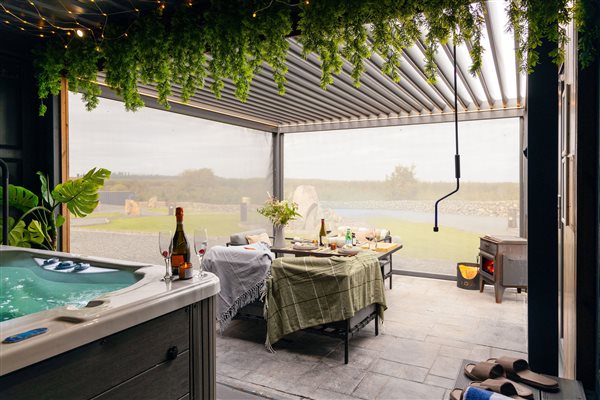 Luxury countryside cabin with private hot tub, spacious covered outdoor terrace, comfortable dining area, modern pergola and beautiful panoramic hill views.
