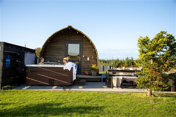 Superior Large Stepless Glamping Pod with private outdoor hot tub at Galloway Retreats in Dumfries and Galloway, Scotland, featuring a wooden pod, spacious outdoor seating area, green lawn and peaceful countryside surroundings.