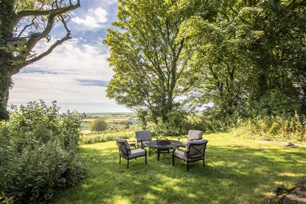 Stable Cottage's private woodland garden with seating are and views across Cornwall