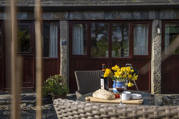 The Wagon exterior with table and chairs, flowers, wine and cheeseboard