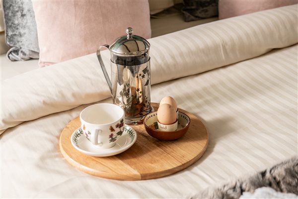 tea tray on crisp striped linen bed sheets