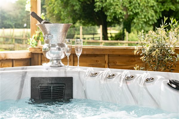 Hot Tub with Prosecco and glasses and views across green field surrounded by woodland