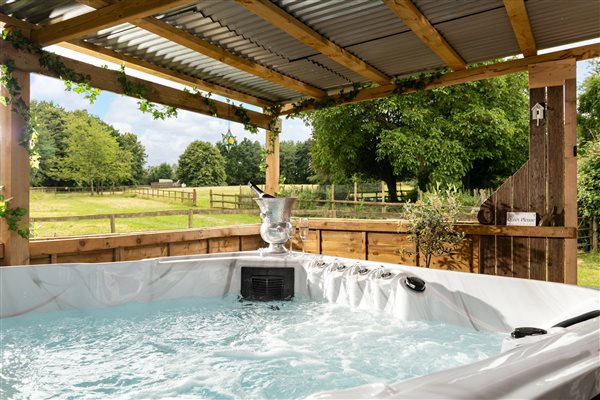 Hot Tub with Prosecco and glasses and views across green field surrounded by woodland