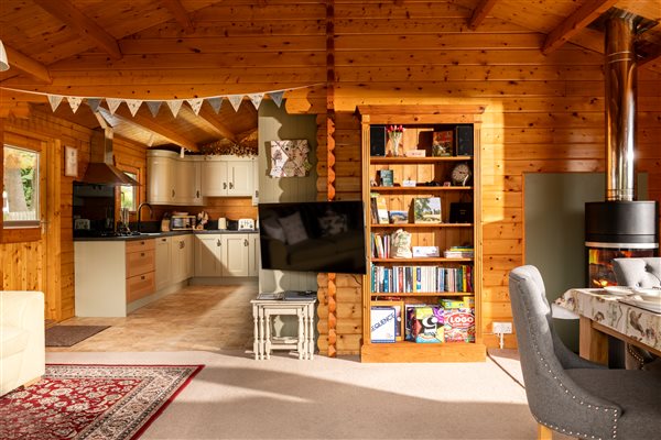 Spacious open plan living room with kitchen, dining table, log burner and sofa and TV/bookshelf