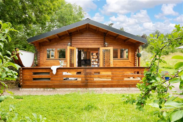 Log cabin in green garden with blue sky