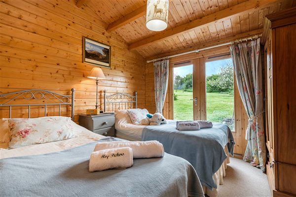 Bedroom with twin beds and double doors leading out into gardens