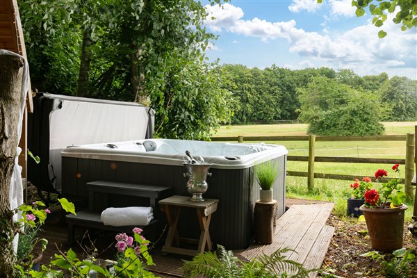 Hot Tub with Prosecco and glasses and views across green field surrounded by woodland