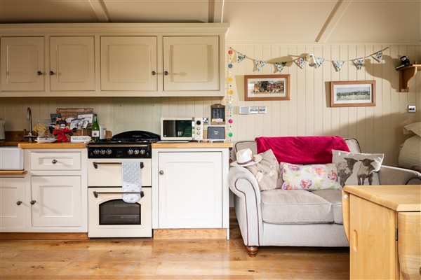 Shepherds hut interior with kitchen next to sofa