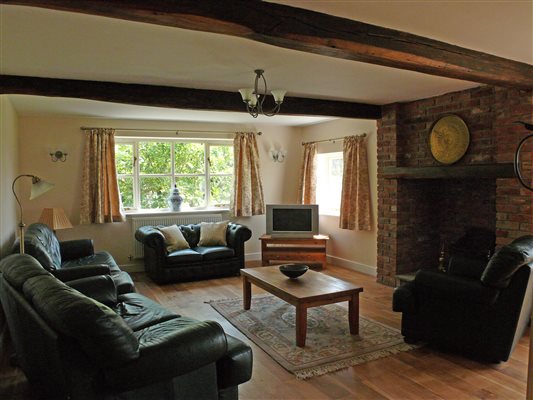 Traditional lounge/living room with log burner and wooden beams.