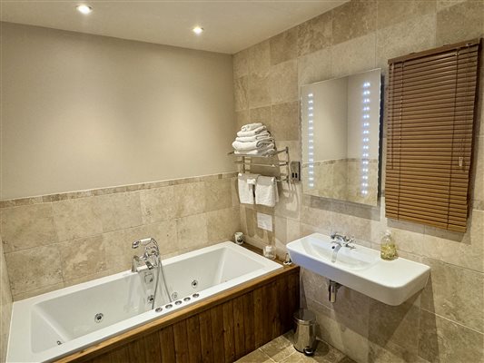 Bathroom with Jacuzzi bath and walk in shower at Ty Gwair 5 - Luxury Hay barn conversion at Snowdonia Holidays Tyddyn Du Farm. Ideal base to re-charge or look for adventures in North Wales.