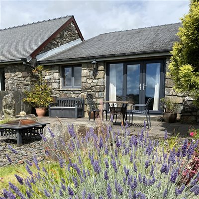 Garden and patio outside y Stabal suite 2 at Snowdonia Holidays Tyddyn du Farm. Dog friendly cottages near Snowdon and Zip World, Eryri beaches and mountains and attractions. accommodation with views.