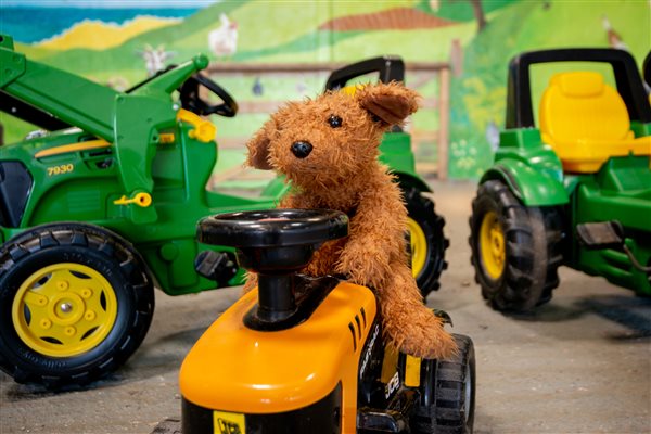 Teddy bear driving tractor in play barn