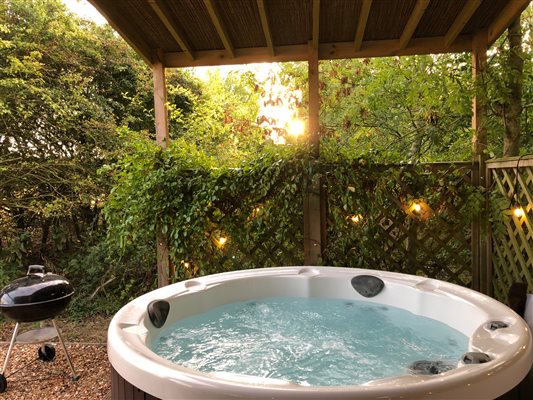 A covered area with a private hot tub and BBQ