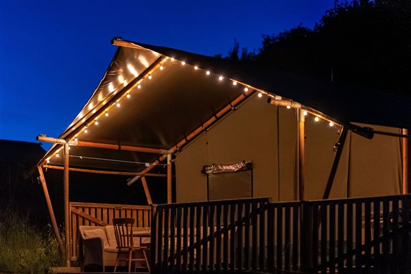 Glamping safari tent at night with decking lights